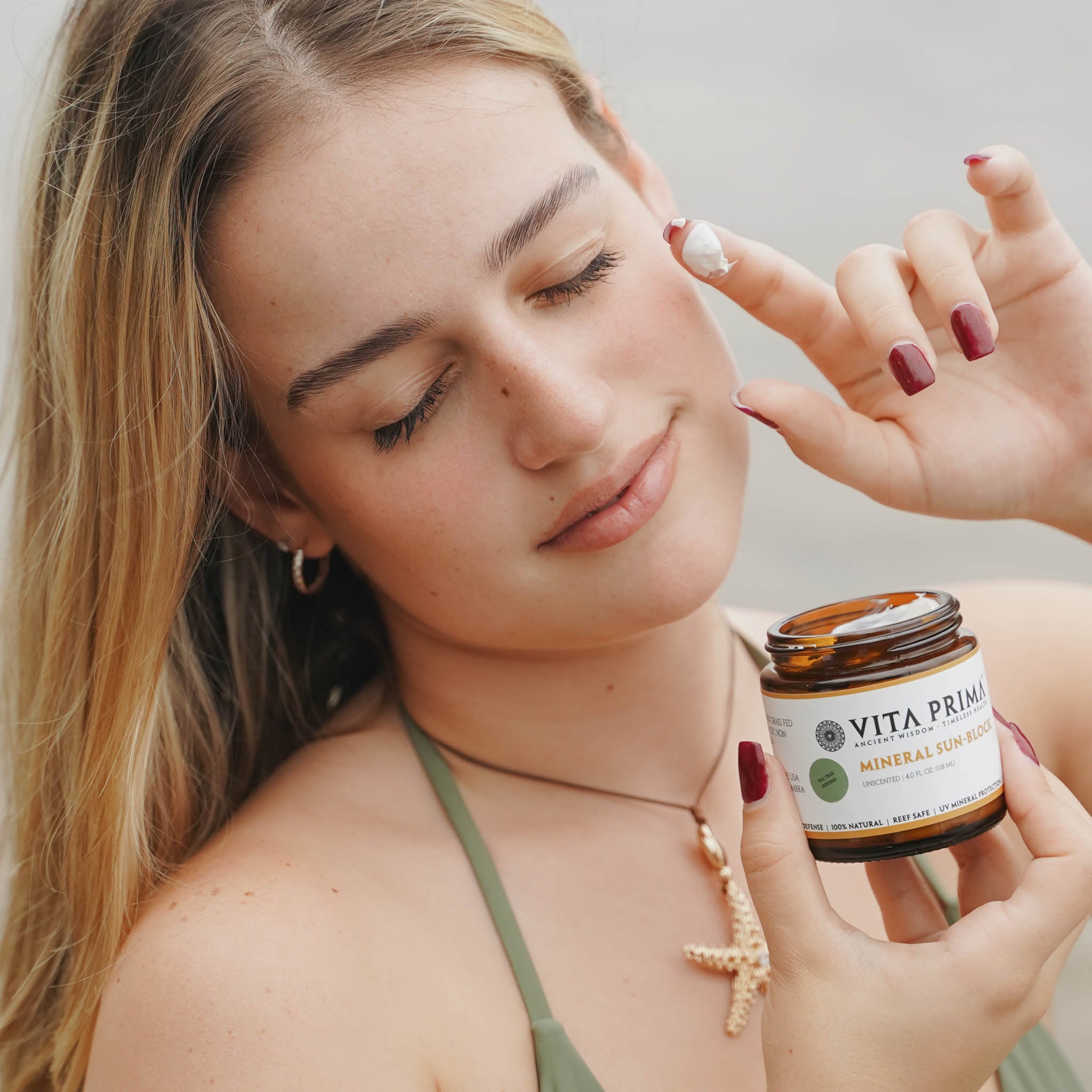 Woman applying cream to her face with a jar of Vita Priam product.
