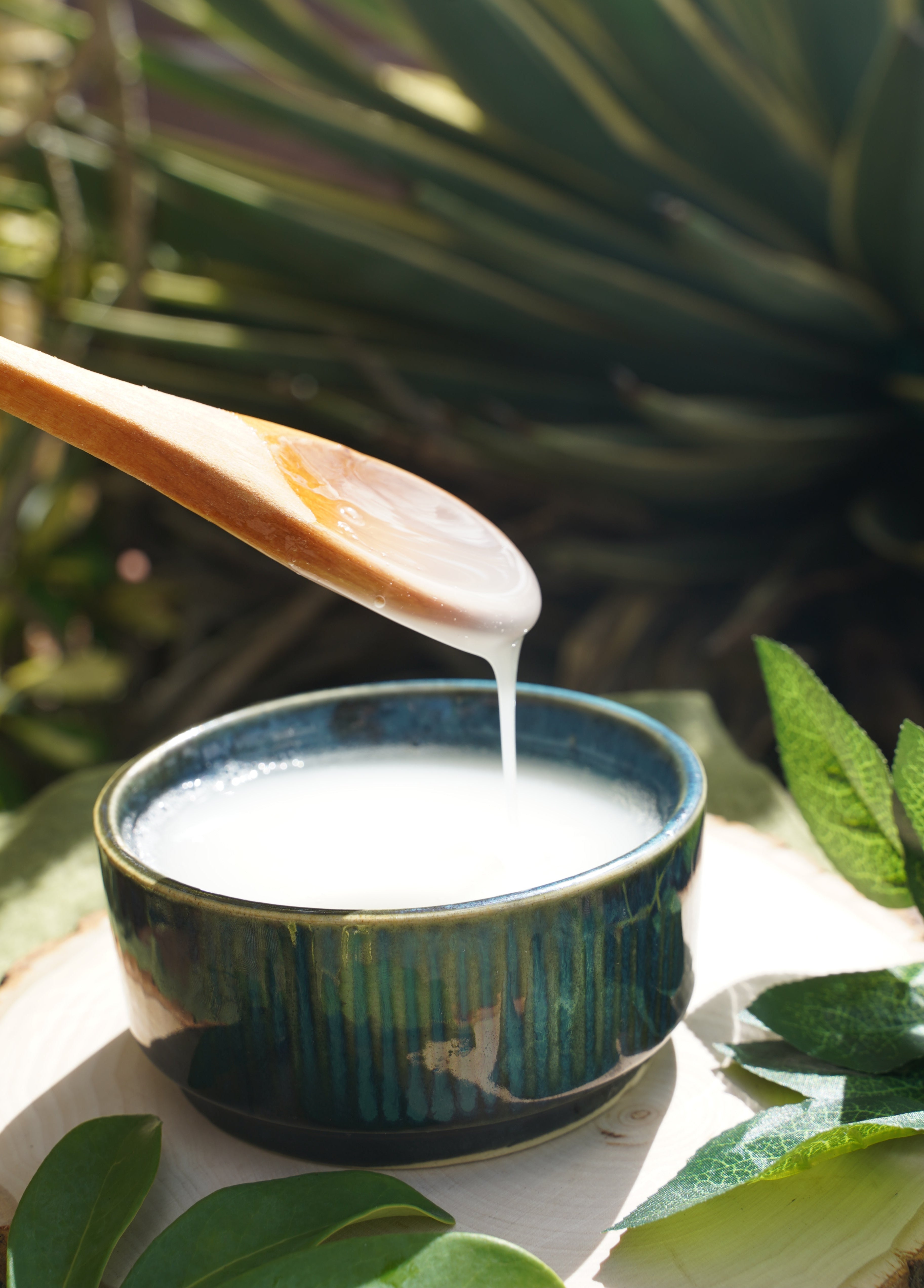 spoon with shampoo in a decorative tin held against a leafy background