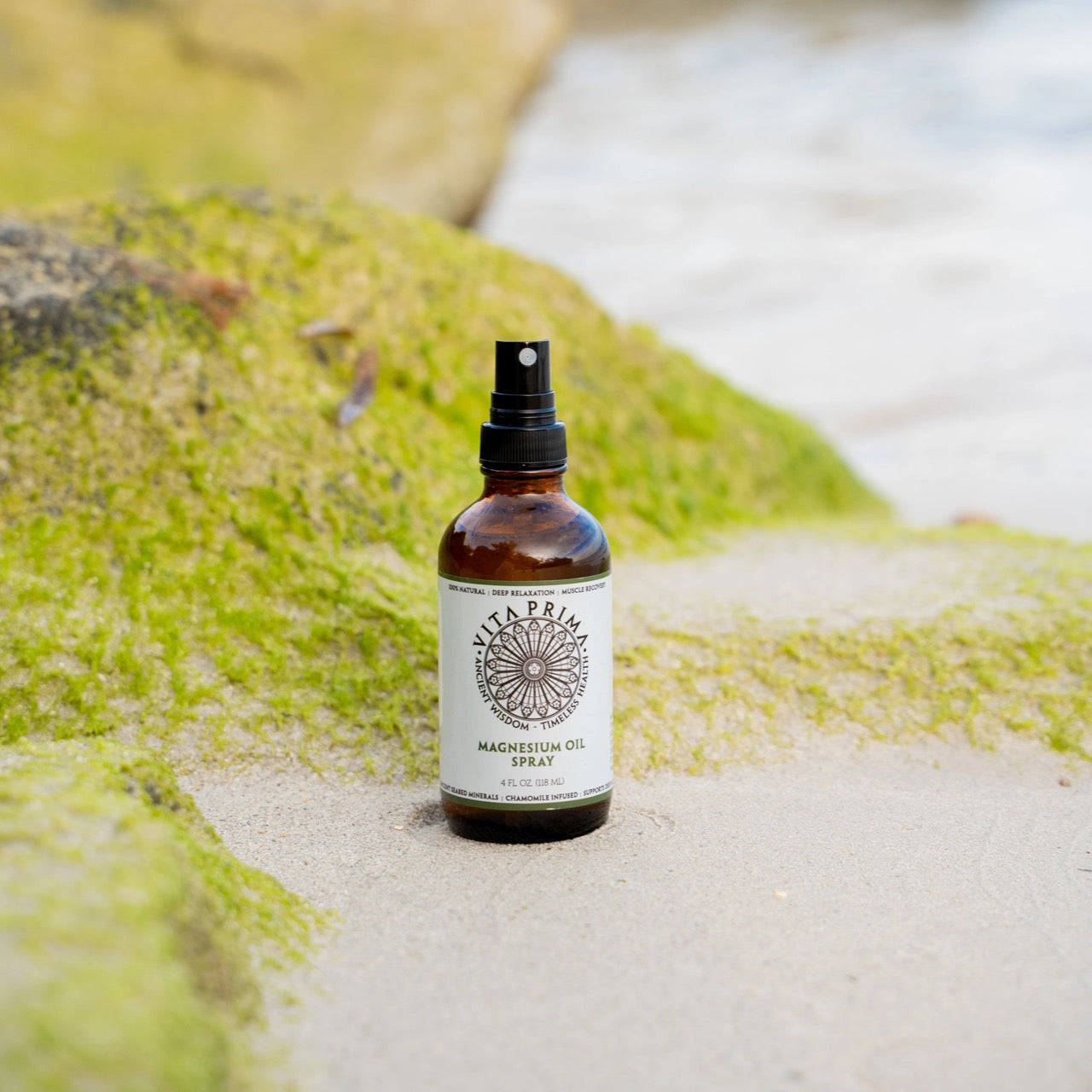 Bottle of magnesium oil spray on a beach with green algae.