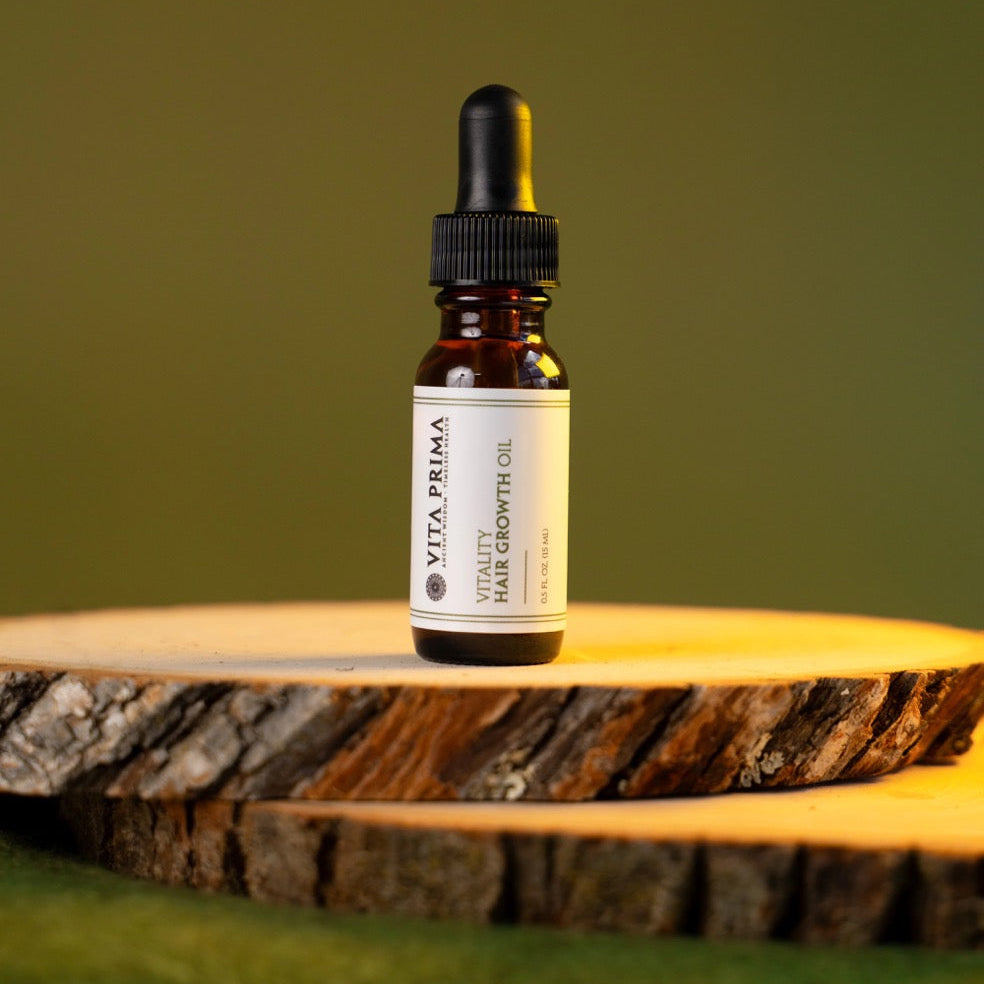 Vita Prima hair growth oil bottle on a wooden surface with a green background