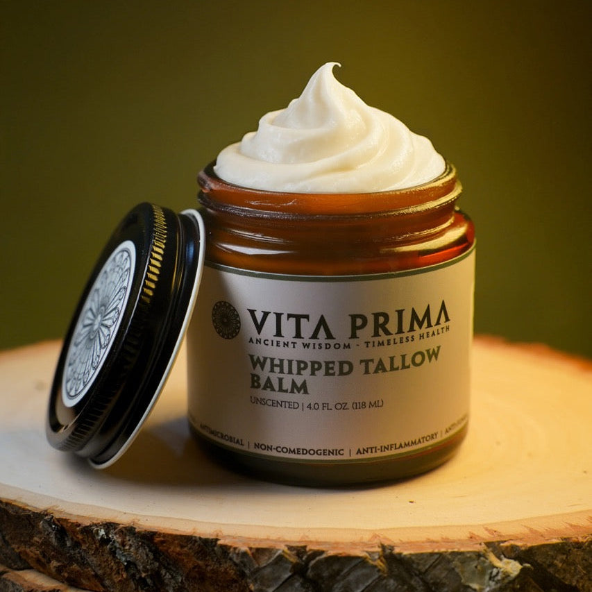 Vita Prima whipped tallow balm jar on a wooden surface with a dark background
